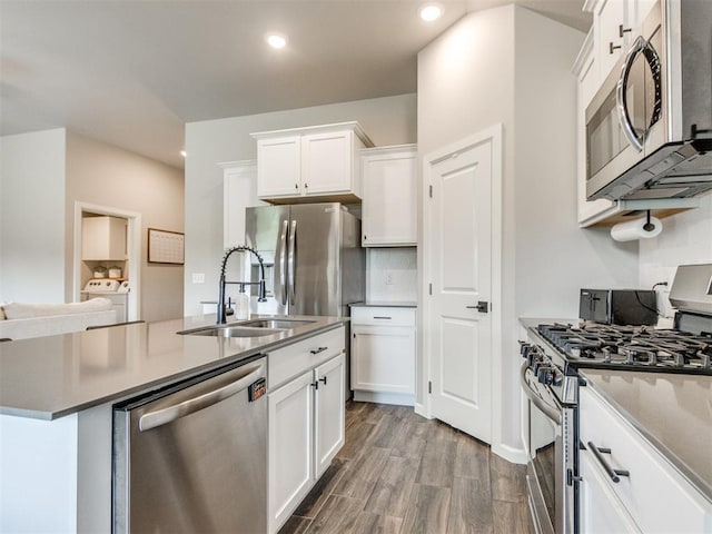 kitchen with washing machine and clothes dryer, a sink, stainless steel appliances, recessed lighting, and white cabinetry