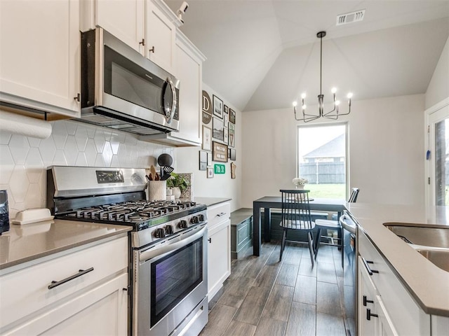 kitchen featuring backsplash, appliances with stainless steel finishes, plenty of natural light, and an inviting chandelier