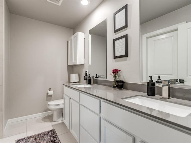 bathroom with double vanity, toilet, baseboards, and a sink
