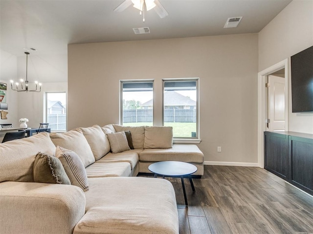 living room featuring visible vents, dark wood finished floors, ceiling fan with notable chandelier, and baseboards