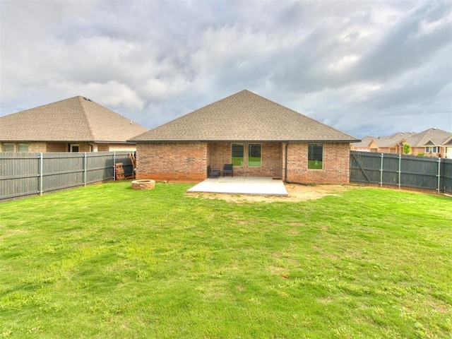 rear view of house with a fenced backyard, a lawn, a patio area, and brick siding