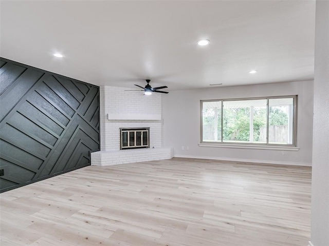 unfurnished living room with a brick fireplace, wood finished floors, baseboards, recessed lighting, and a ceiling fan