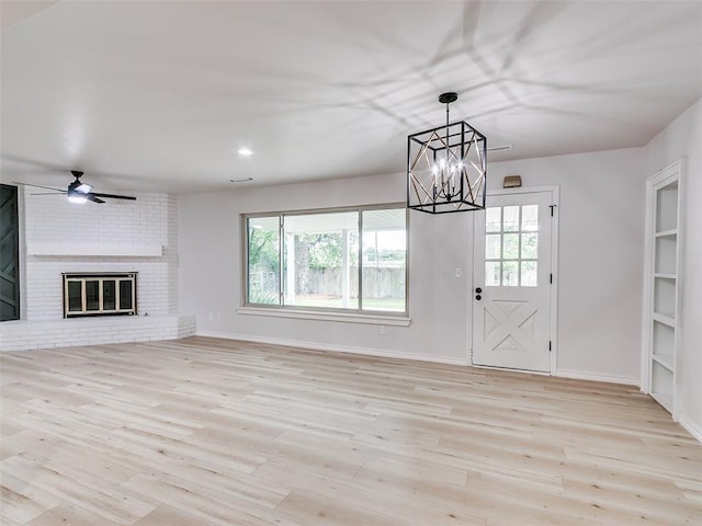 unfurnished living room with baseboards, ceiling fan with notable chandelier, wood finished floors, and a wealth of natural light