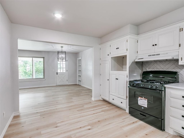 kitchen featuring light wood-type flooring, baseboards, black gas range oven, under cabinet range hood, and white cabinetry