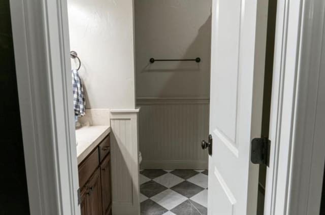 bathroom with vanity, a wainscoted wall, and toilet