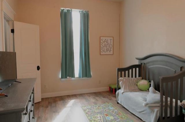 bedroom featuring baseboards, multiple windows, and wood finished floors