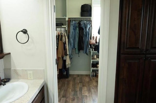 bathroom with vanity, wood finished floors, and a spacious closet