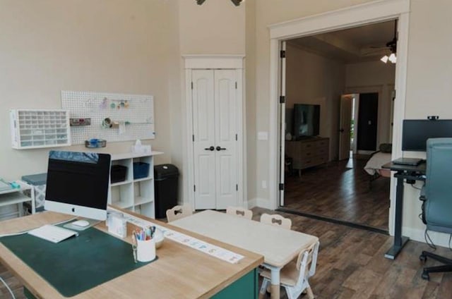 home office with ceiling fan, wood finished floors, and a high ceiling