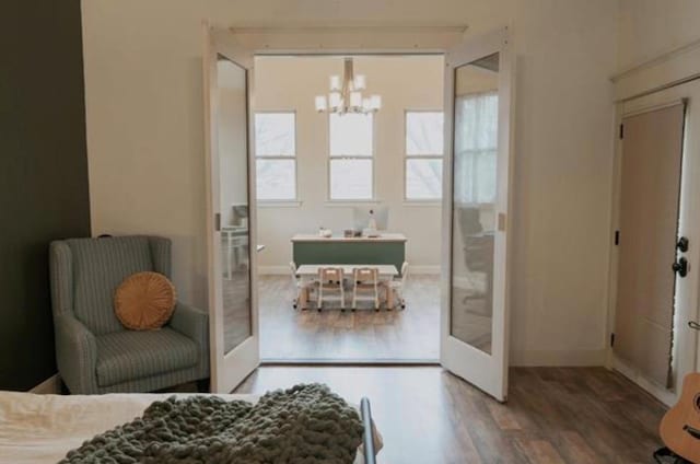 bedroom with baseboards, wood finished floors, and a notable chandelier