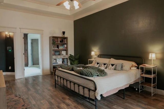 bedroom with crown molding, a ceiling fan, a tray ceiling, and wood finished floors