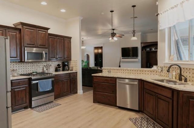 kitchen featuring ceiling fan, a sink, light wood finished floors, stainless steel appliances, and backsplash