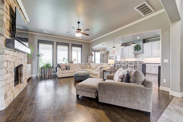 living room featuring arched walkways, baseboards, ceiling fan, and visible vents