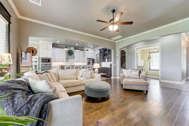 living room with arched walkways, baseboards, dark wood finished floors, and ceiling fan with notable chandelier