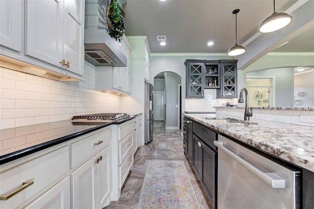 kitchen featuring crown molding, a sink, arched walkways, premium range hood, and stainless steel appliances