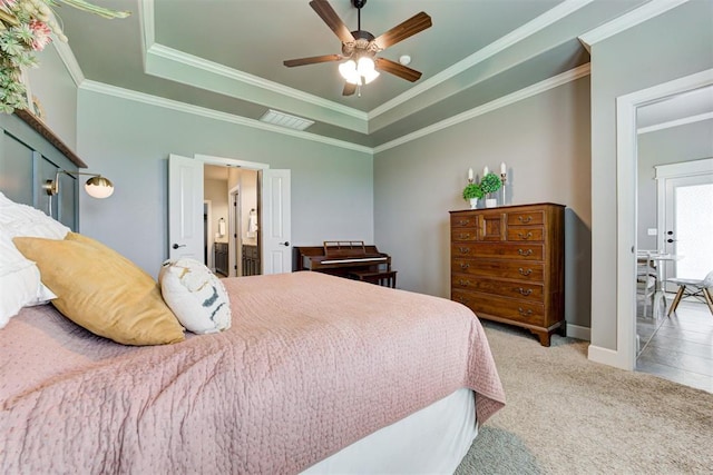 carpeted bedroom with visible vents, crown molding, baseboards, a tray ceiling, and a ceiling fan