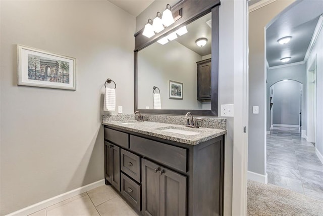 bathroom with double vanity, baseboards, a sink, and tile patterned flooring