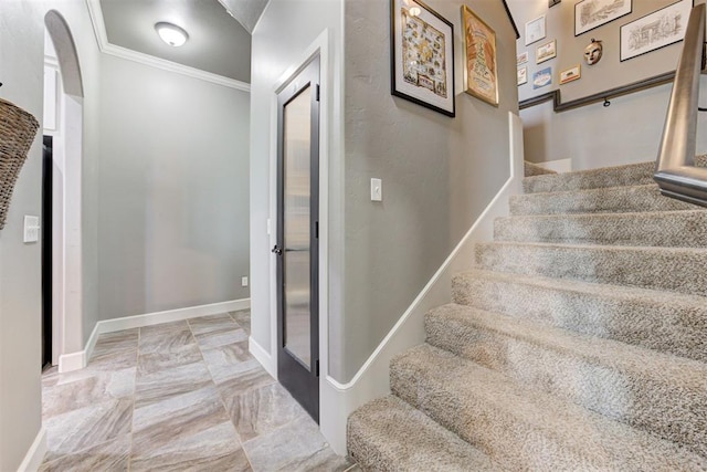 stairs with crown molding, marble finish floor, and baseboards