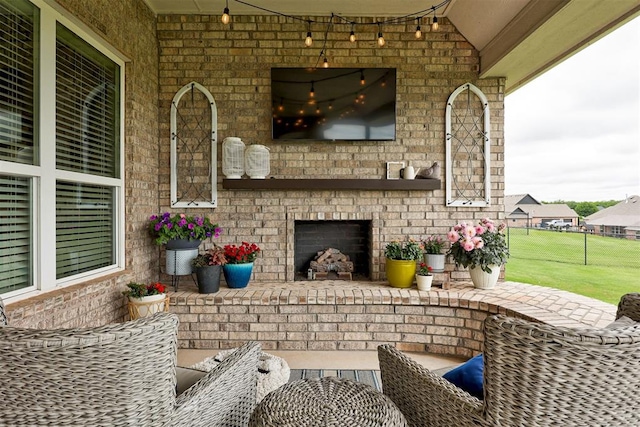 view of patio featuring an attached garage, fence, and an outdoor brick fireplace