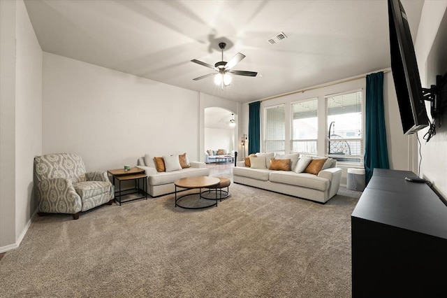 living area with carpet floors, arched walkways, a ceiling fan, and visible vents