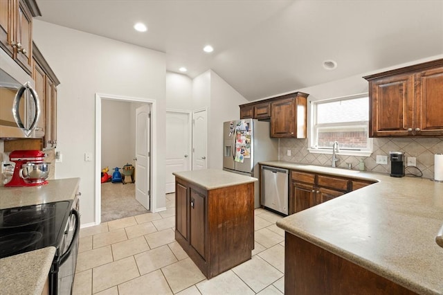 kitchen with decorative backsplash, a kitchen island, appliances with stainless steel finishes, vaulted ceiling, and a sink