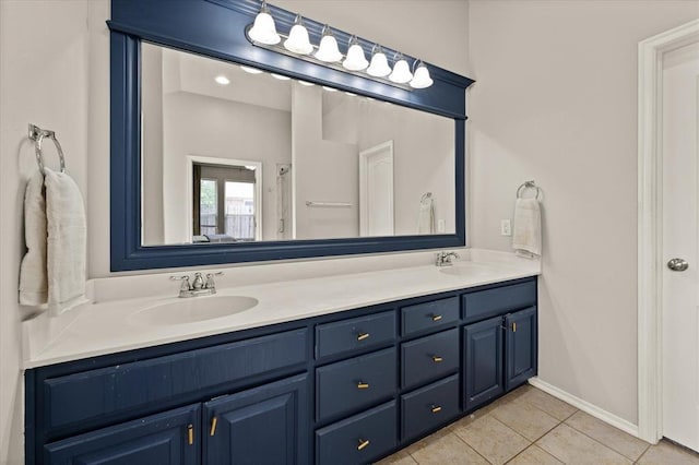 full bath featuring double vanity, a sink, baseboards, and tile patterned floors