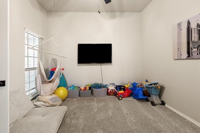 recreation room with baseboards, ceiling fan, and carpet