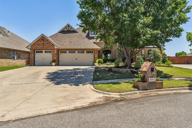 view of front of property featuring roof with shingles, brick siding, concrete driveway, a garage, and a front lawn
