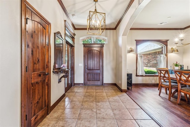 entrance foyer with arched walkways, a chandelier, crown molding, and plenty of natural light