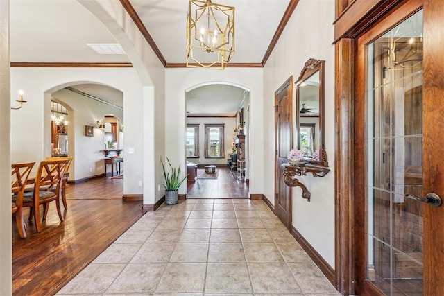 foyer featuring arched walkways, visible vents, a chandelier, and crown molding