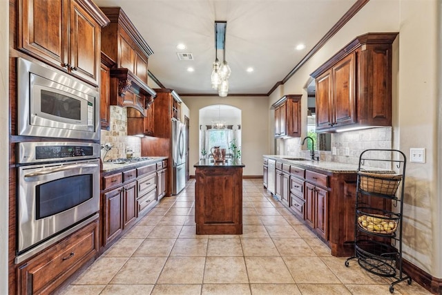 kitchen with a sink, tasteful backsplash, ornamental molding, a kitchen island, and appliances with stainless steel finishes