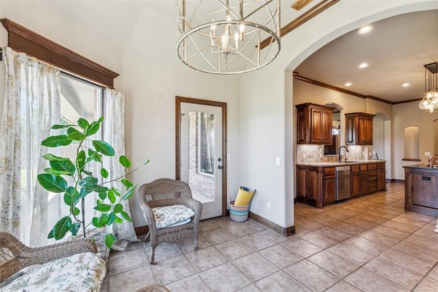 kitchen with an inviting chandelier, stainless steel dishwasher, baseboards, arched walkways, and ornamental molding