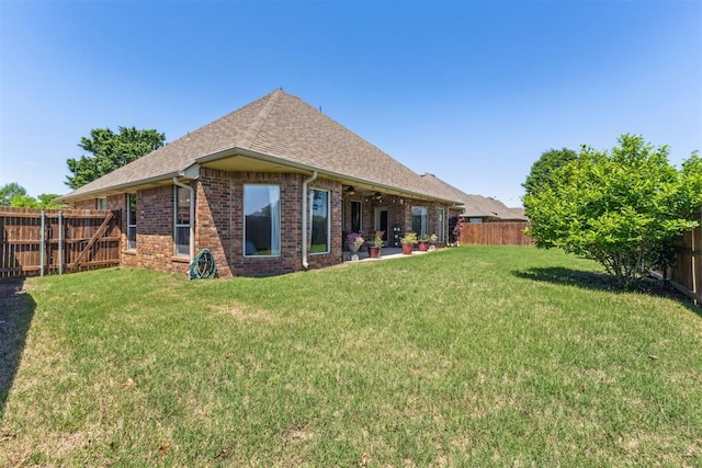 back of house featuring ceiling fan, brick siding, a fenced backyard, and a yard