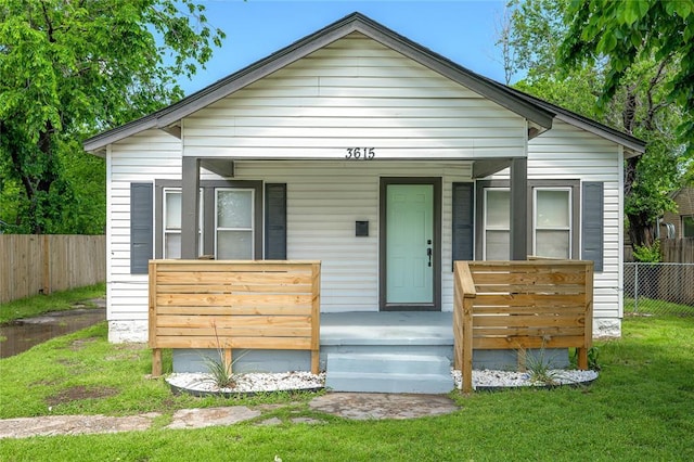bungalow-style home with fence, covered porch, and a front yard