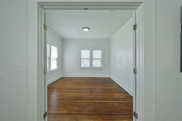 empty room with baseboards, ornamental molding, and dark wood-style flooring