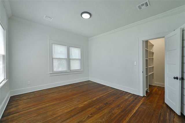 spare room with a wealth of natural light, dark wood-style floors, and visible vents