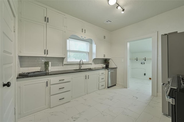 kitchen featuring visible vents, appliances with stainless steel finishes, dark countertops, a sink, and white cabinets