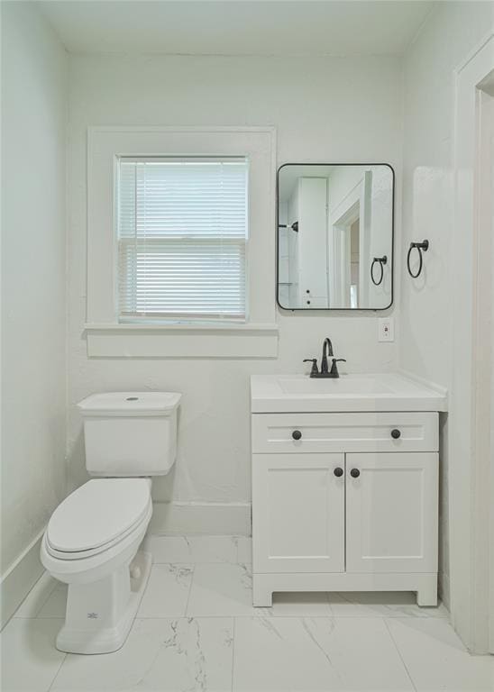 bathroom with toilet, baseboards, marble finish floor, and vanity