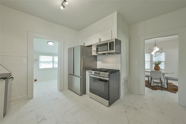 kitchen with white cabinets, a chandelier, appliances with stainless steel finishes, and marble finish floor