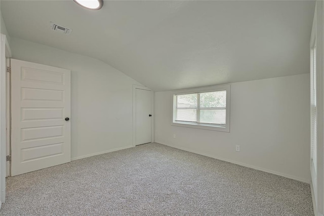interior space featuring baseboards, carpet flooring, vaulted ceiling, and visible vents
