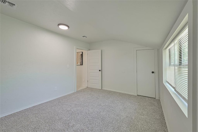 unfurnished room with light colored carpet, baseboards, visible vents, and vaulted ceiling