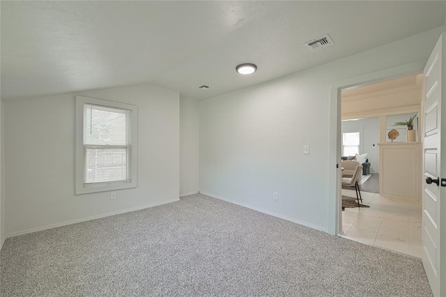 interior space featuring visible vents, vaulted ceiling, multiple windows, and light colored carpet