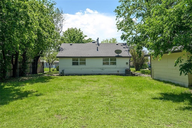 back of house with fence, central AC unit, and a lawn