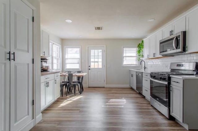 kitchen with light countertops, light wood finished floors, appliances with stainless steel finishes, and tasteful backsplash