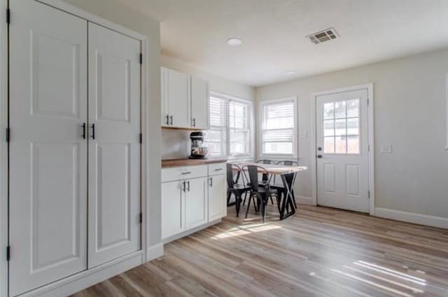 interior space featuring visible vents, white cabinets, a healthy amount of sunlight, and light wood-type flooring