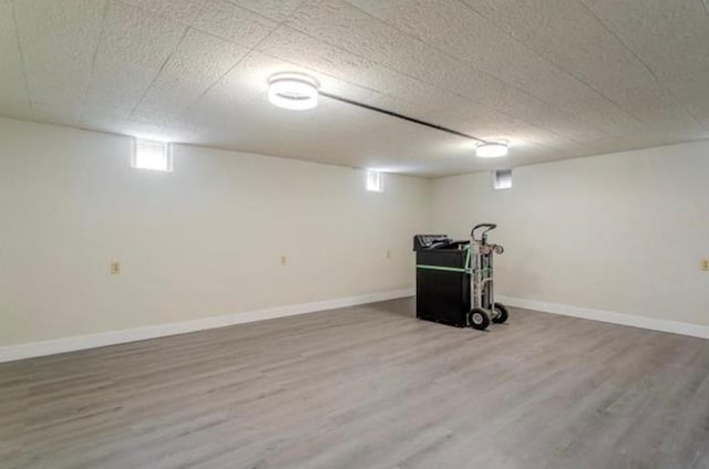 below grade area with baseboards and wood finished floors