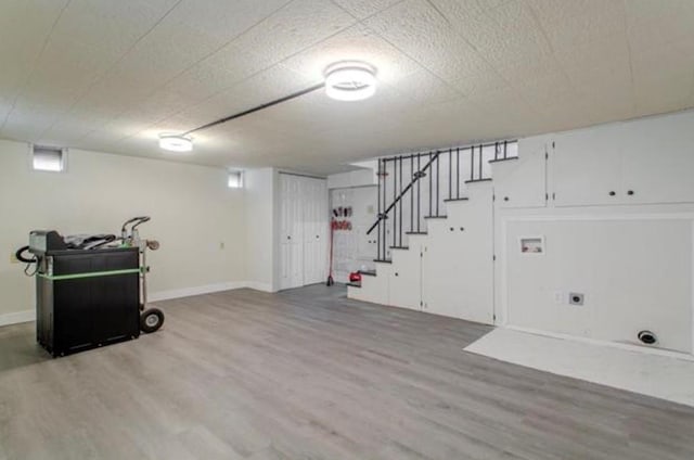 basement featuring baseboards, wood finished floors, and stairway