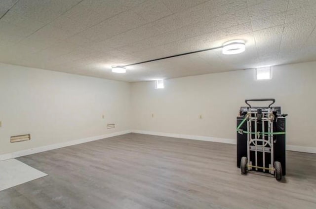 basement featuring baseboards and wood finished floors