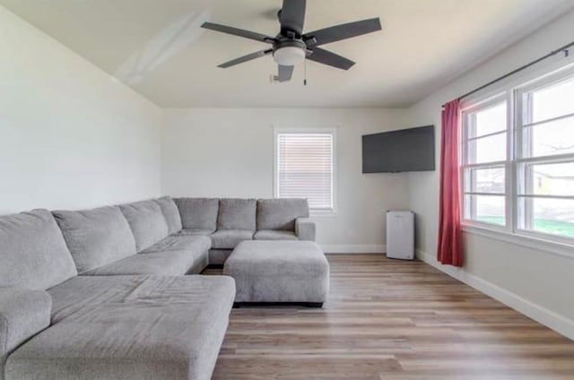 living room featuring ceiling fan, baseboards, and light wood finished floors