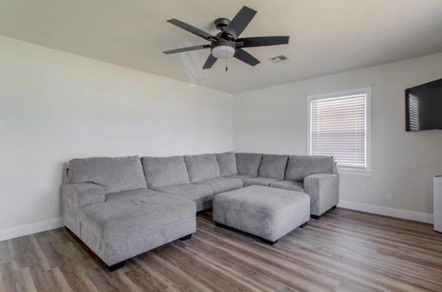 living room with baseboards, ceiling fan, wood finished floors, and visible vents
