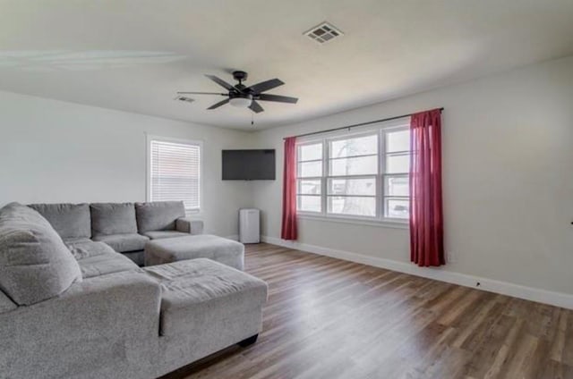 living area with a ceiling fan, baseboards, visible vents, and wood finished floors